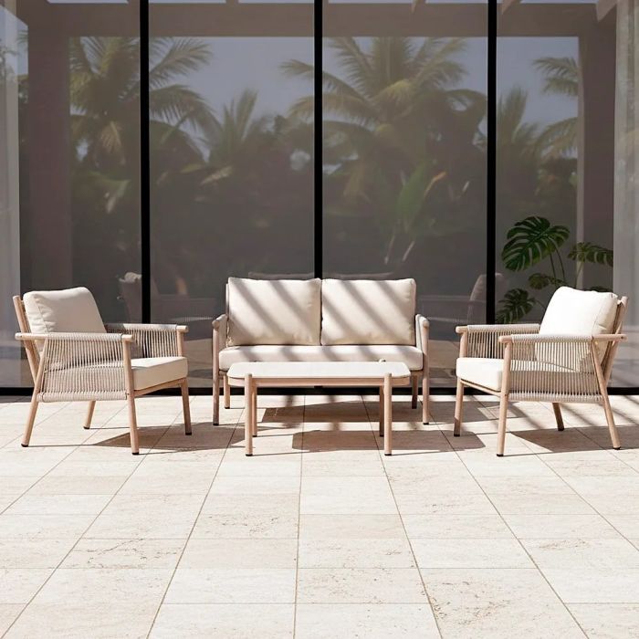 Conjunto de sofá jardín en ratán, acero color natural, cojines blancos y piedra blanca.