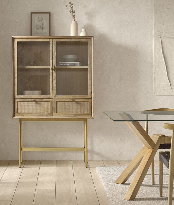 Vitrina en madera natural y puertas de vidrio con base dorada.