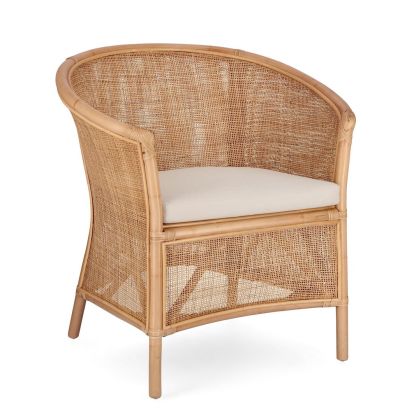 Sillón tropical con estructura de ratán natural y cojín tono beige.