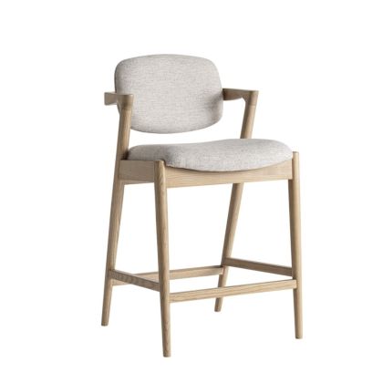Taburete en madera de fresno natural tapizado en tejido beige.
